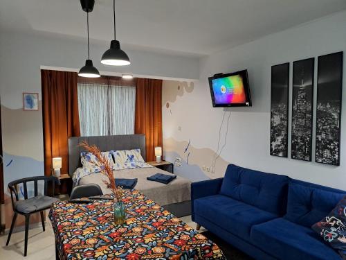 a living room with a blue couch and a tv at Студио Цвят/ Studio Colour in Blagoevgrad