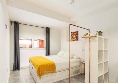 a white bedroom with a bed and a window at LoftinMalaga in Málaga
