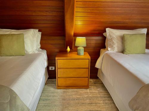a bedroom with two beds and a night stand with a lamp at Casa Três Rios - Campos do Jordão in Campos do Jordão