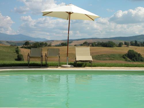twee stoelen en een parasol naast een zwembad bij Podere Sant'Antonio in Buonconvento