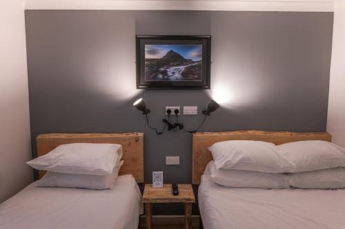 a bedroom with two beds and a picture on the wall at Roam West in Fort William