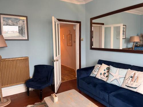 a living room with a blue couch and a mirror at Harbour View Ground Floor Flat with Private Parking, only 5 Mins walk to harbour in Brixham