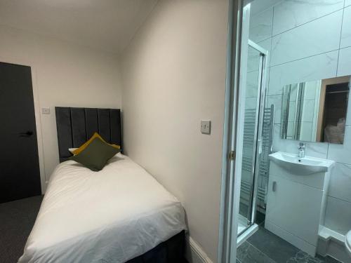 a small bedroom with a bed and a sink at Woodford Hotel in London
