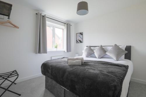 Un dormitorio con una cama con paredes blancas y una ventana en StayRight 4 Bedroom, 3 Bathroom House Near M4 - 15 mins to Cardiff & Newport, en Cardiff