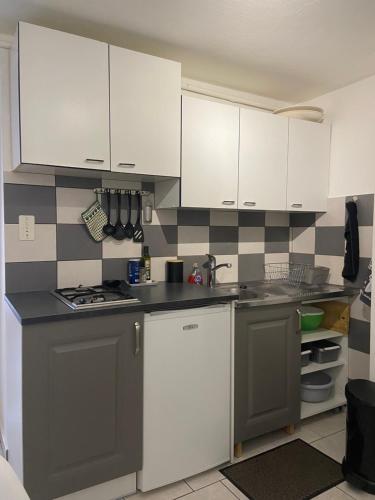 une petite cuisine avec des armoires blanches et un évier dans l'établissement Paisible, à Bassens