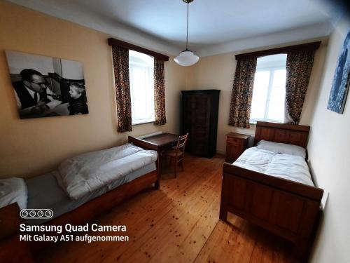 a bedroom with two beds and a desk and windows at Landhaus Just in Maria Elend