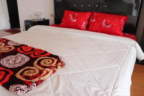 białe łóżko z czerwonymi poduszkami na górze w obiekcie HW. Hubers Hotel, Bar & Resto w mieście Laguboti