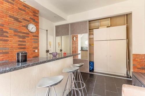 a kitchen with white cabinets and a brick wall at apartment with garden in Neuilly-sur-Seine