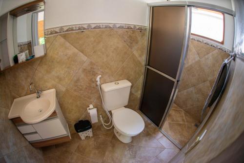 a small bathroom with a toilet and a sink at Chalés Sapucaí Pousada in São Bento do Sapucaí