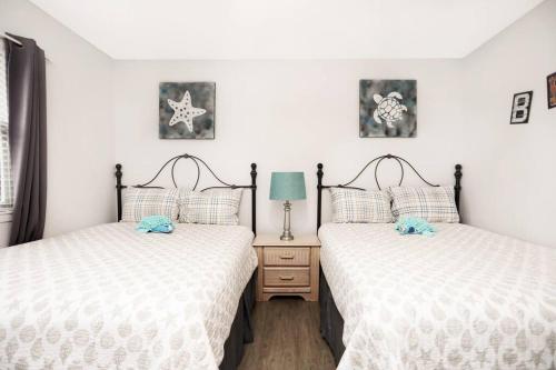 2 aparte bedden in een kamer met witte muren bij Emerald Shores: Steps from the Gulf, Navarre Beach in Navarre