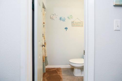 een badkamer met een wit toilet in een kamer bij Emerald Shores: Steps from the Gulf, Navarre Beach in Navarre