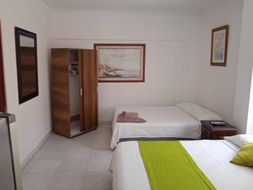 ein Hotelzimmer mit 2 Betten und einem Kühlschrank in der Unterkunft Habitación I frente a la playa ( Bocagrande ) in Cartagena de Indias