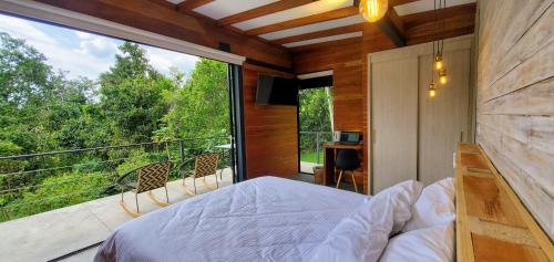 ein Schlafzimmer mit einem Bett und einem großen Fenster in der Unterkunft Ecohotel Alma in Calarcá