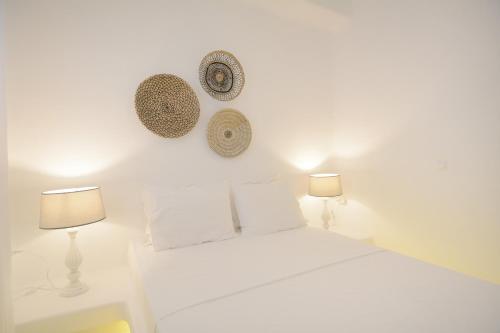a white bedroom with two lamps and a bed at Sea Breeze Mykonos in Mykonos