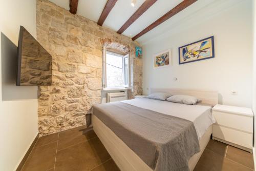 a bedroom with a bed and a stone wall at Apartman Škor in Komiža
