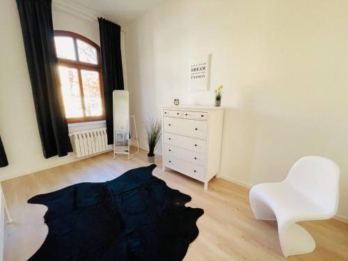a living room with a white dresser and a white chair at YourFavoriteBed Designerapartments Zwickau Zentrum in Zwickau