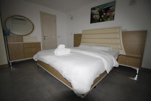 um quarto com uma cama grande com lençóis brancos e um espelho em סוויטות נופי החרמון - Hermon View Suites em Majdal Shams