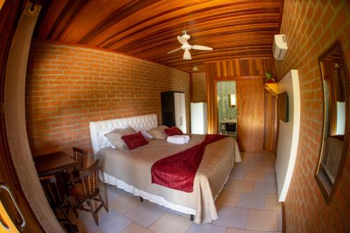 1 dormitorio con cama y pared de ladrillo en Chalés Sapucaí Pousada en São Bento do Sapucaí