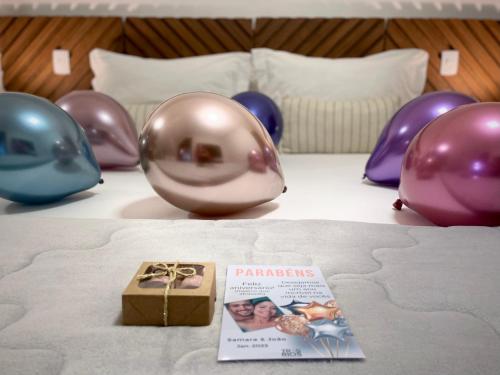 a table with balloons and a box on a bed at Casa Três Rios - Campos do Jordão in Campos do Jordão