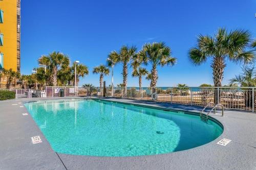 a swimming pool with palm trees in a resort at Ocean Blue - Ocean View Condos by Coastline Resorts in Myrtle Beach