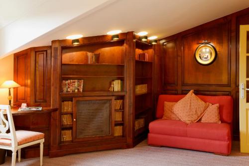a living room with a red chair and a book shelf at Hôtel L'Yeuse - Teritoria in Châteaubernard