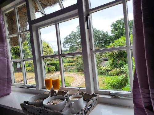 einen Tisch mit Frühstücksspeisen und Getränken vor dem Fenster in der Unterkunft Castle Hill Cottage on a Scheduled Monument in Kenilworth