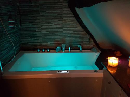 a bathroom with a blue tub with a candle at Castle Hill Cottage on a Scheduled Monument in Kenilworth