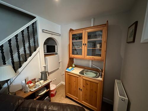 a small kitchen with a sink and a cabinet at Cottage en-suite room with private lounge in Bridport