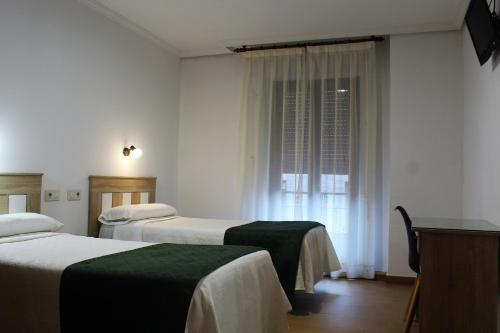 トレドにあるオスタル マドリードのベッド2台と窓が備わるホテルルームです。