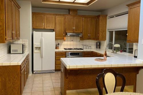 a kitchen with wooden cabinets and a white refrigerator at Beautiful peaceful desirable home in Madera Rancho in Madera