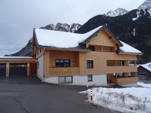a house covered in snow with mountains in the background at Haus Amatschon in Brand