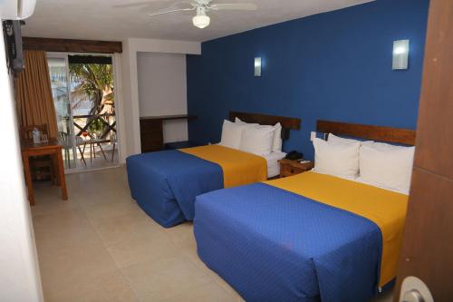 2 camas en una habitación de color azul y amarillo en Lorencillo Miramar, en Tampico