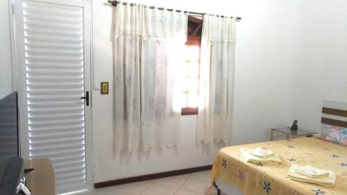 アチバイアにあるPousada Montanha da Pedra Grandeのベッドルーム1室(ベッド1台付)、窓付きのドアが備わります。