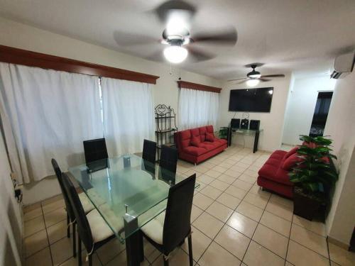 a living room with a glass table and a red couch at Central Departamento in Mazatlán
