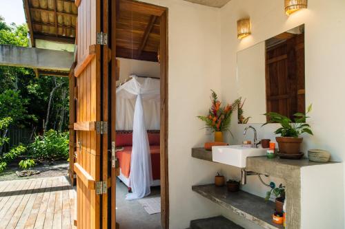 a bathroom with a sink and a dress hanging in the doorway at Casa Canoa - Praia de Algodões in Marau