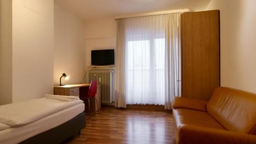 ミュンヘンにあるHotel Pegasusのベッド、ソファ、窓が備わるホテルルームです。