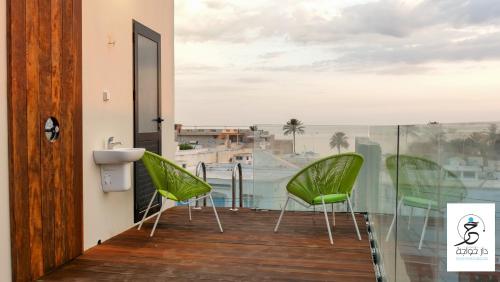 a balcony with green chairs and a view of the ocean at Dar Khouadja maison d’hôtes in Mahdia