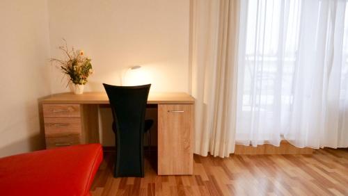 a desk with a chair in front of a window at Hotel Pegasus in Munich