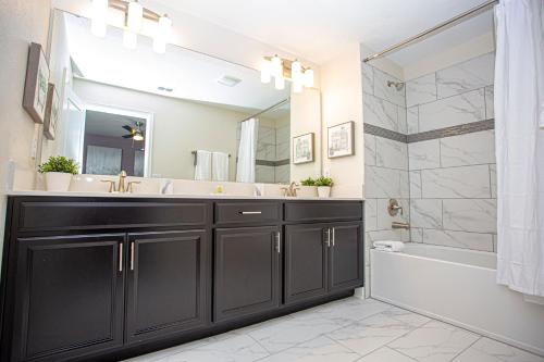 uma casa de banho com um toucador preto e uma banheira e lavatório. em Marvelous 5 Bedroom w/ Pool Close to Disney 4811 em Kissimmee