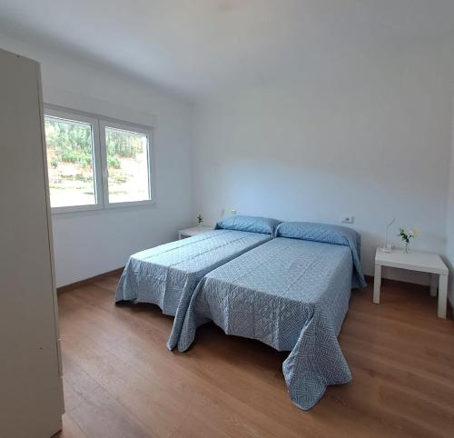 a white bedroom with a bed with a blue blanket at Casa das Laxas, recién reformada con 5 dormitorios en entorno natural in Porto do Son