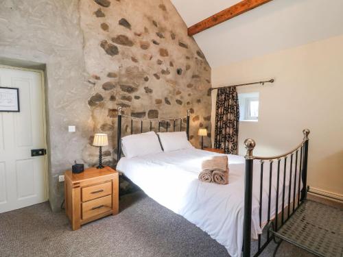ein Schlafzimmer mit einem Bett und einer Steinwand in der Unterkunft Rosies Cottage in Bushmills