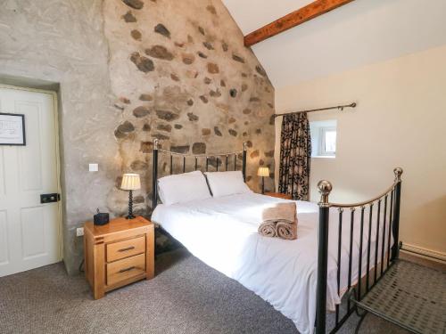 a bedroom with a bed and a stone wall at Rosies Cottage in Bushmills