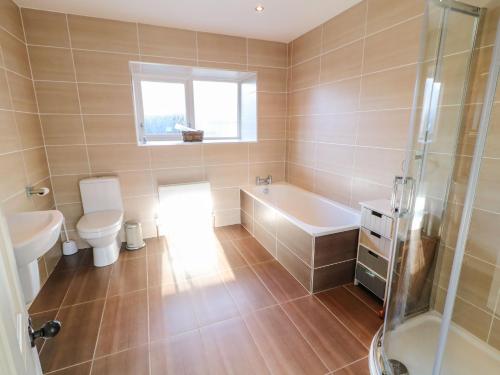 ein Badezimmer mit Badewanne, Toilette und Waschbecken in der Unterkunft Rosies Cottage in Bushmills