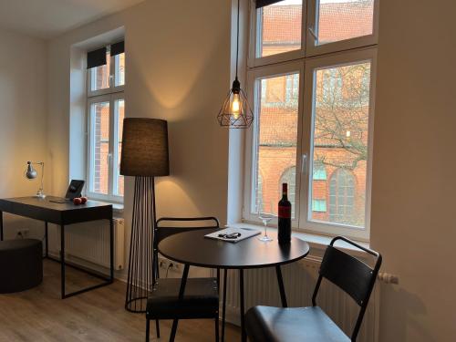 ein Wohnzimmer mit einem Tisch und einer Flasche Wein in der Unterkunft Apartmenthaus Buxtehude St -Petri-Platz Studiowohnung 3 in Buxtehude