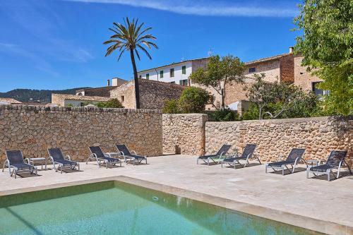 una piscina con sillas, una pared y una palmera en Ca' n Beia Suites - Adults Only, en Alaró