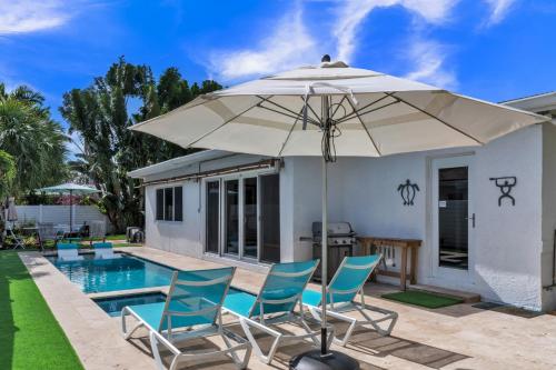 um pátio com cadeiras e um guarda-sol ao lado de uma piscina em Sandcastles & Sunshine at Towering Palms of Wilton Manors residence em Fort Lauderdale