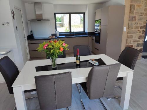 une table blanche et des chaises avec un vase de fleurs dessus dans l'établissement les hirondelles, à Péaule