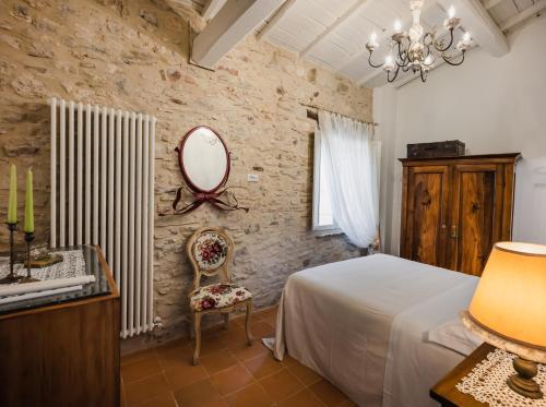 una camera con letto, specchio e sedia di Locanda Mescoglia a Corciano