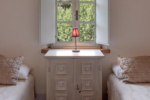 a lamp sitting on a cabinet next to two beds at Podere Ferranino at Ville Ferrano in San Giovanni dʼAsso