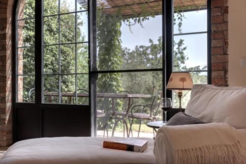a bedroom with a bed and large glass windows at Podere Ferranino at Ville Ferrano in San Giovanni dʼAsso